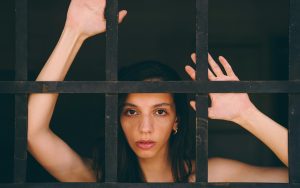Portrait of a woman behind bars, expressing introspection and contemplation.