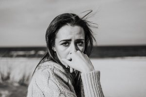 A monochrome portrait of a woman with pensive expression at the beach.